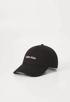 Zwarte katoenen baseballpet met een wit geborduurd "Calvin Klein" logo aan de voorkant. Klassiek ontwerp met een gebogen klep en zespanelenconstructie.