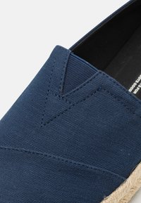 Marineblå stof slip-on sko med en tekstureret overdel og diskré syninger; har en jute reb sål for ekstra greb.
