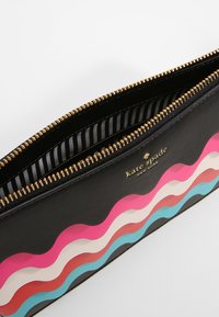 Sort lynlåspose med farverige bølge mønstre i pink, rød, beige og blå, med guldfarvede detaljer og stribet indvendig foring.