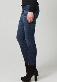 Smal blårandiga jeans med medel tvätt, med en klassisk femfickdesign, smal passform och diskret slitage på låren.