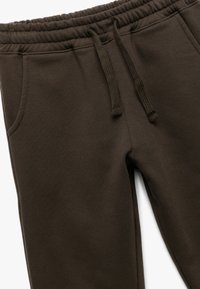 Bruine sweatpants van zacht materiaal, met een elastische tailleband en trekkoord, zijzakken en een gladde textuur.