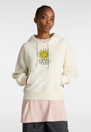 Felpa crema realizzata in un tessuto morbido, con una grafica a forma di sole e il testo "VANS". Sotto, una maglietta rosa stratificata, con una vestibilità rilassata e tasca frontale.