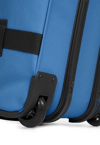 Valigia di tessuto blu con superficie texture, dettagli in plastica nera e una robusta ruota nera rotante per la mobilità.