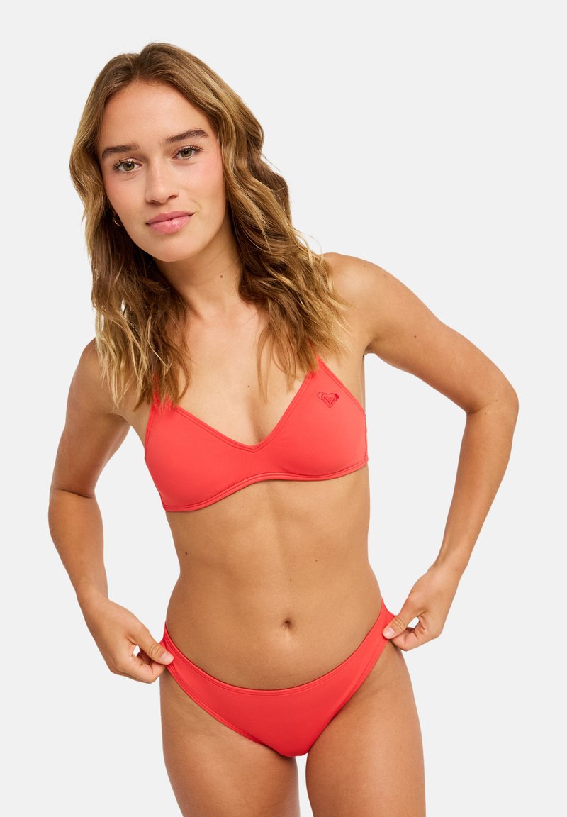 Σετ μπικίνι κοραλλί που περιλαμβάνει τριγωνικό μπούστο με λεπτές τιράντες και αντίστοιχο κάτω μέρος με χαμηλή μέση, κατασκευασμένο από απαλό, ελαστικό ύφασμα.