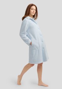 Bata de baño de color azul claro, esponjosa, de longitud hasta la rodilla, con frente abotonado, cuello con muesca y dos bolsillos laterales, con una tela texturizada.