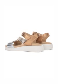 Bronze- og sølv sandaler med to justerbare stropper, en solid hvid platformssål og en glat tekstur. Minimalistisk design.