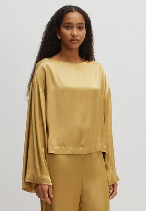 Gouden satijnen top met lange, brede mouwen en een ronde halslijn. Soepele textuur en verkorte silhouet. Gecombineerd met bijpassende gouden broek.