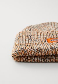 Gorro de malha com uma mistura de fios em creme, laranja e azul-marinho, com um design texturizado em canelado e um patch retangular com o logo na lateral.