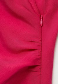 Fuchsiová šatová tkanina s hladkým povrchem, která má skrytý boční zip a jemné nařasení podél švu pro designový detail.