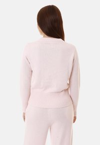 Maglione a maglia rosa chiaro con orlo e polsini a coste, caratterizzato da un design semplice e classico. Texture soffice, lunghezza media e colletto rotondo.