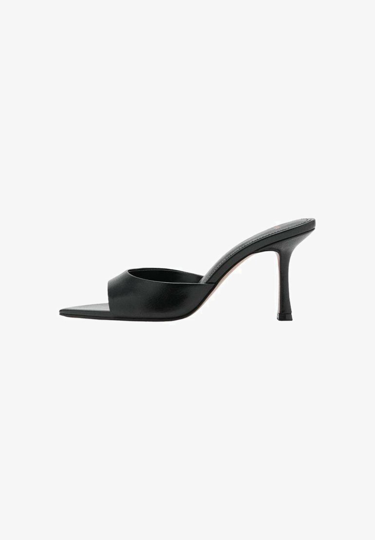 Mules de cuero negro sin puntera con un diseño curvado y un tacón de aguja. Textura suave y estilo minimalista, con un corte frontal.