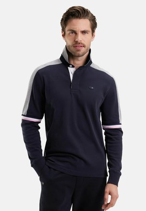 Polo-shirt à manches longues bleu marine avec panneaux d'épaule gris, poignets côtelés avec des rayures rose et blanche, et une patte de boutonnage à deux boutons.