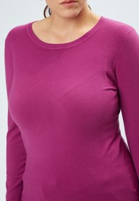 Suéter ajustado de manga larga en rosa brillante, hecho de un suave tejido de punto liso con un cuello redondo acanalado y una silueta ceñida.