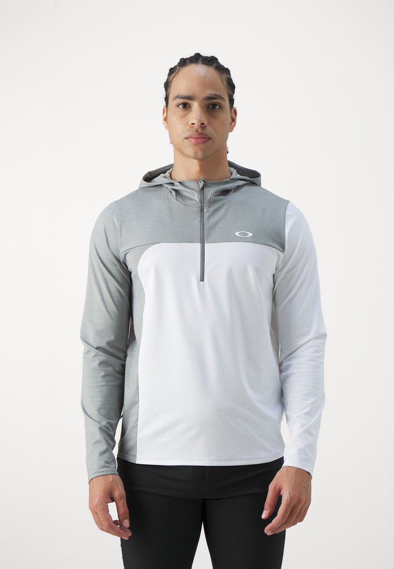 Pull-over sportif à capuche avec une partie supérieure grise et une partie inférieure blanche. Fabriqué en tissu lisse avec un col zippé et un accent de logo.