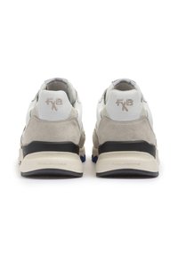Sneaker in suede bianco e grigio chiaro con suola nera, caratterizzate da un marchio ricamato sul retro e un design testurizzato.