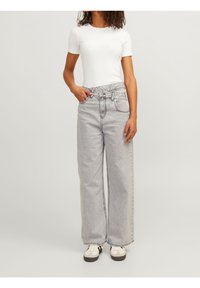 Ljust grå vida jeans med hög midja, framfickor och kontrasterande sömmar, kombinerade med en figurnära vit t-shirt med kort ärm och sneakers.