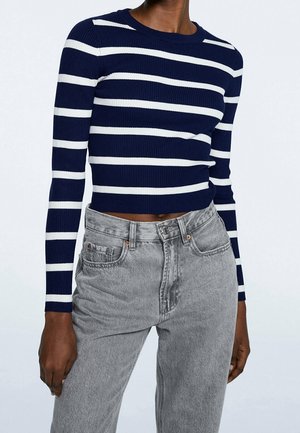 Maglione a righe navy e bianche, a costine, con maniche lunghe, abbinato a jeans grigi a vita alta con un classico design a cinque tasche.