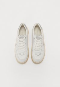 Sneakers bianchi in pelle texturizzata, con punta perforata, lacci piatti e suola in gomma beige. Presentano un accento grigio sul tallone.