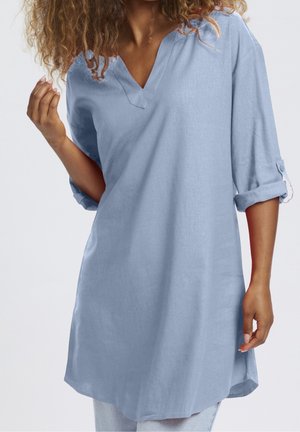 Jasnoniebieska lniana tunika z dekoltem w kształcie litery V i rękawami o długości za łokieć, o luźnym kroju i podwiniętych mankietach. Miękka faktura, gładkie wykończenie.