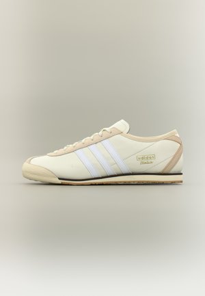 Krém és bézs színű Adidas Italia sportcipő fehér három csíkkal és bézs talppal, oldalnézetben semleges háttéren.