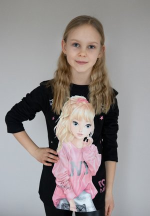 Schwarzes Langarmshirt mit einem großen Grafikdesign eines Cartoon-Mädchens mit langen blonden Haaren, das einen rosa Pullover mit dem Schriftzug "NY" trägt.