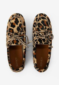 Des chaussures à enfiler en imprimé léopard avec des motifs marron et noir, présentant une texture semblable à du daim et des lacets en tissu. Doublure intérieure marron visible.