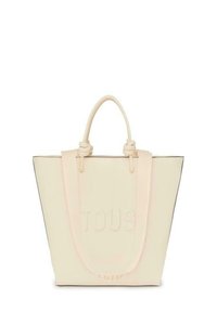 Borsa tote bianca in pelle con logo "TOUS" impresso. Presenta lunghe maniglie annodate e bordi neri a contrasto. Forma rettangolare.