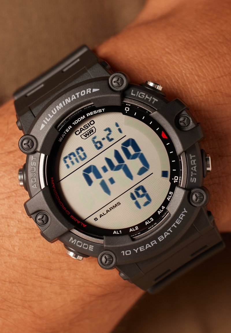 Montre numérique noire avec un grand affichage. Caractéristiques : étanchéité jusqu'à 100 mètres, cinq alarmes et une batterie d'une durée de dix ans. Bracelet en résine.