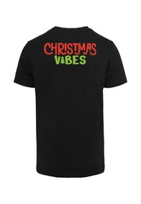 Black short-sleeve t-shirt featuring the text "CHRISTMAS" in red and "VIBES" in green on the upper back, with a tree icon between the words.
