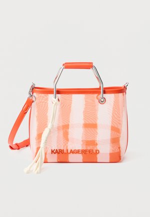 Sac fourre-tout transparent orange avec poignées argentées, bordure orange, pompon blanc, et logo "KARLLAGERFELD" sur le devant.