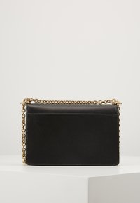 Borsa a tracolla nera in pelle con superficie testurizzata, cinturino a catena dorato, forma rettangolare e design minimalista. Nessun ulteriore componente o accento.