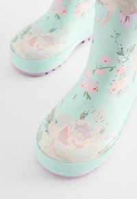 Stivali da pioggia floreali in verde menta con una finitura lucida. Presentano fiori rosa pallido e crema, suola in gomma testurizzata in lavanda.