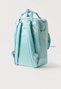 Tirkizni ruksak s glatkim, sjajnim materijalom. Ima podesive trakice, ručku na vrhu i bočne džepove za pohranu.