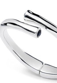 Bracelet jonc en argent avec une finition lisse et polie et un design courbé. Présente un petit accent en pierre précieuse noire à une extrémité.