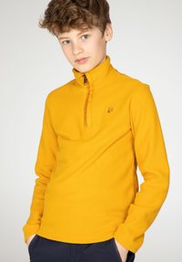 Pullover in pile giallo con collo alto, zip frontale a quarto di giro e tessuto testurizzato. Presenta un piccolo logo sul petto.