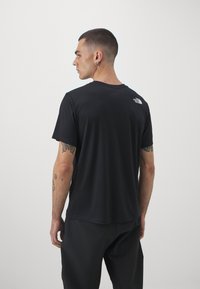 T-shirt preta de mangas curtas, feita de um tecido suave, com gola redonda e um pequeno logótipo branco nas costas, perto da gola.