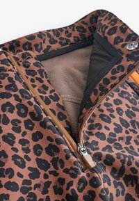 Kurtka w panterkę na brązowym tle z czarnymi plamami. Posiada zamknięcie na zamek błyskawiczny i miękką podszewkę. Wytrzymała tekstura tkaniny.