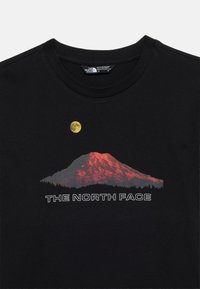 Μαύρο μπλουζάκι με κόκκινο γραφικό βουνού, κίτρινο φεγγάρι από πάνω και το κείμενο «THE NORTH FACE» κάτω από το σχέδιο του βουνού.