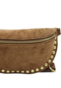 Sac à main en daim marron avec une fermeture éclair dorée, forme ovale, et des clous ronds décoratifs le long du bord. Texture douce, design minimaliste.