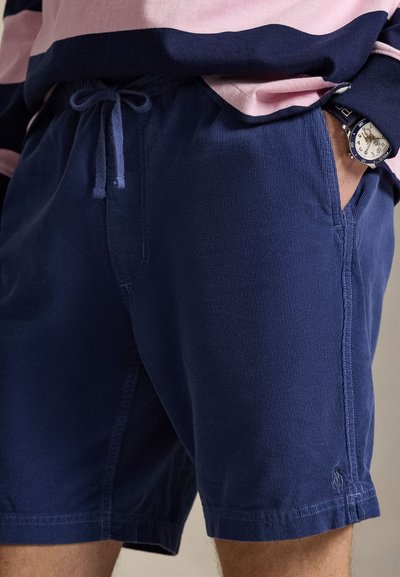 Σκούρο μπλε σορτς με κορδόνι στη μέση, κατασκευασμένο από υφή υλικό. Πλαϊνές τσέπες και εμφανείς ραφές.