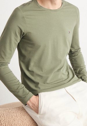 Langärmliges olivgrünes T-Shirt aus weicher Baumwolle mit Rundhalsausschnitt und kleinem Logodetail auf der Brust. Angenehm taillierte Passform.