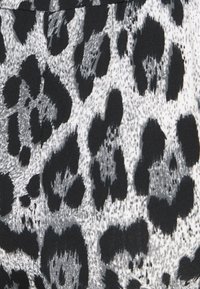 Zwart-wit luipaardprint stof met verschillende texturen, featuring duidelijke vlekken en een gladde, iets rekbare uitstraling.