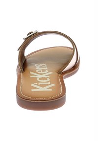 Sandaña de cuero marrón con tira trasera y hebilla de plata, suela plana y plantilla color beige con la marca "Kickers".