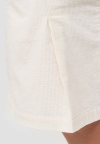 Ljusbeige ribbade kordskjorts med vertikal ribbning, med en sidoklyfta och rak fåll. Mjuk textur och ren finish.