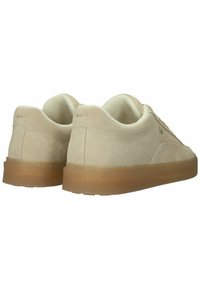 Een paar beige suède sneakers met bruine doorzichtige zolen, zichtbare stiksels en een gevoerde binnenvoering, gezien vanaf de achterkant en zijkant.