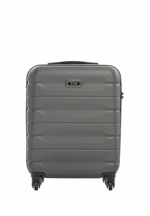 Twarda szara walizka z czterema obrotowymi kółkami i górnym uchwytem do przenoszenia, stojąca pionowo na białym tle.