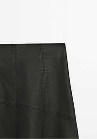 Gonna in pelle nera con finitura liscia, caratterizzata da cuciture verticali e un design strutturato. Estetica minimalista senza elementi visibili in metallo.