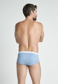 Męskie niebieskie bawełniane slipy z białą gumką w pasie, o gładkiej fakturze i dopasowanym kroju, widoczne z tyłu.