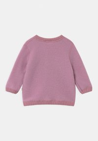 Sweter polarowy w miękkim różu z długimi rękawami, okrągłym dekoltem i ściągaczami. Posiada fakturowane wykończenie oraz małą, wielokolorową metkę.