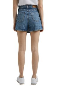 Jeansshorts in Hellblau mit hoher Taille, mit zwei Gesäßtaschen und einem Lederpatch nahe des Bunds. Der Saum ist leicht ausgefranst.
